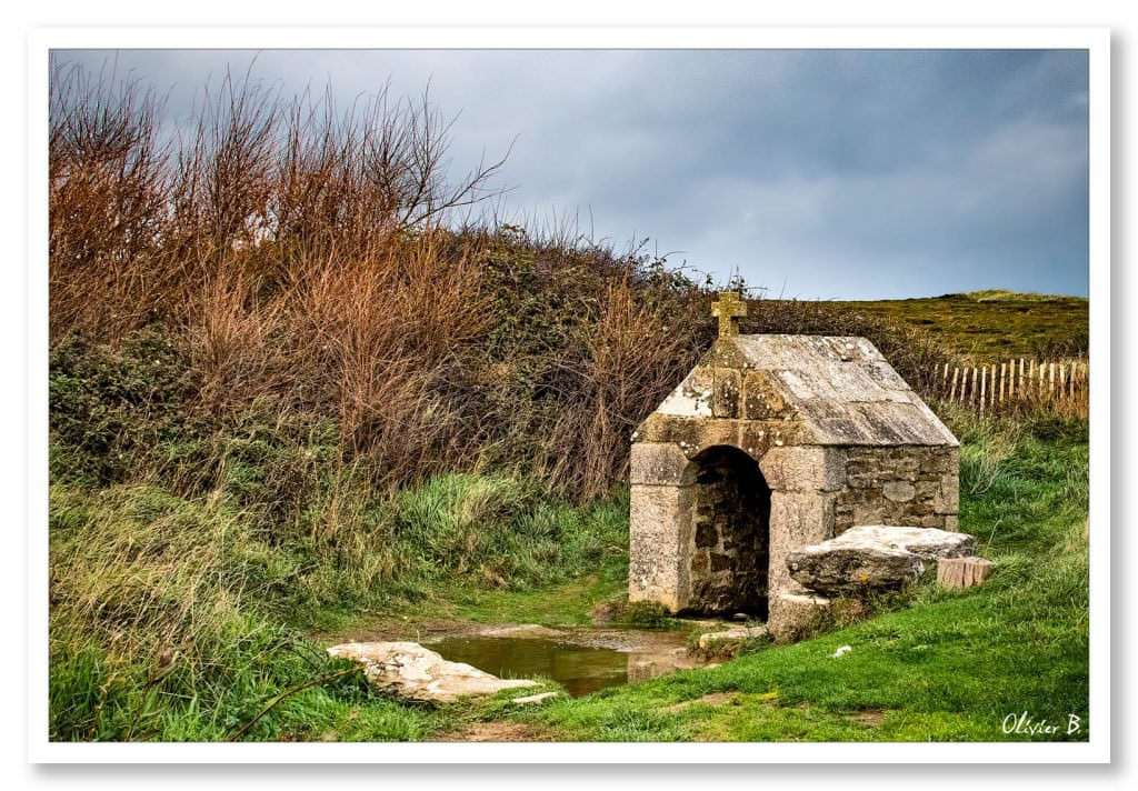 Ancien lavoir en granit au milieu de la lande, entouré d'ajonc et surmonté d'une croix