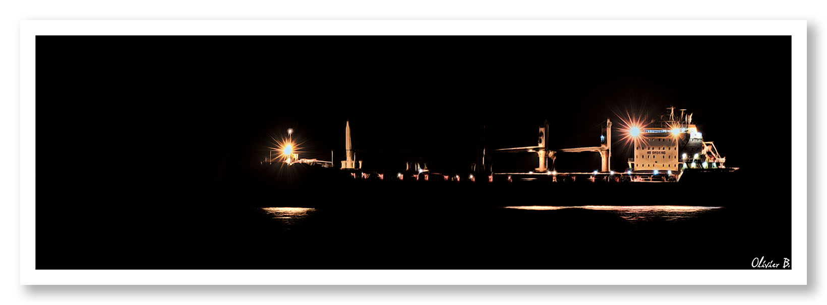 Un cargo sans coque se découpe dans la nuit, illuminé seulement par les lumières qui dessinent le pont