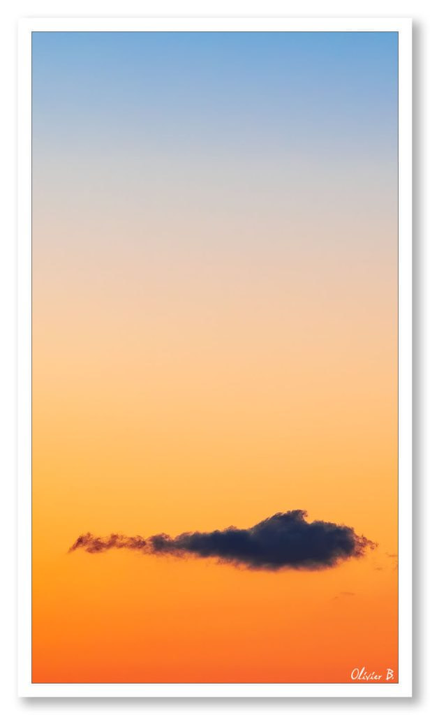 Nuage solitaire dans un ciel dégradé bleu-rouge lors d'un magnifique coucher de soleil